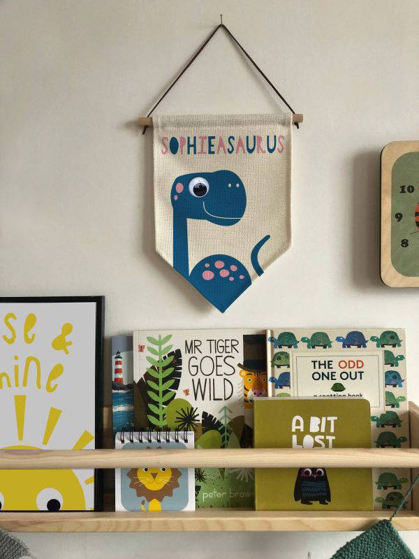 Dinosaur-pennant-Flag-for-Girl Dinosaur flag hung up above a shelf of books in kids nursery